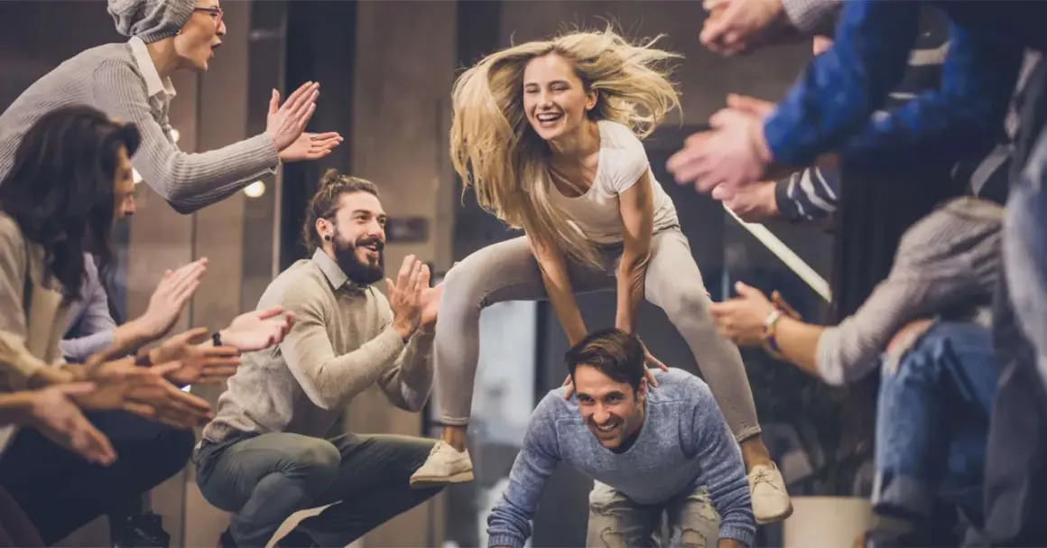 Un gruppo di amici si diverte con giochi da fare in gruppo seduti senza niente, tra risate e applausi.