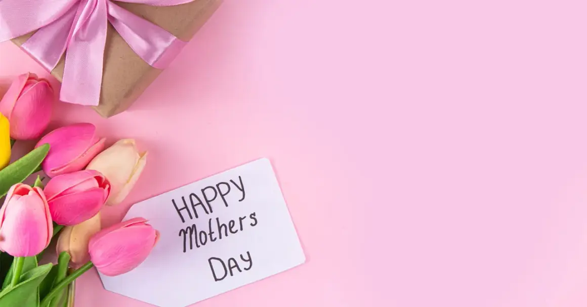 Un regalo incartato con un fiocco rosa e tulipani colorati, pronti per la festa della mamma in Italia.