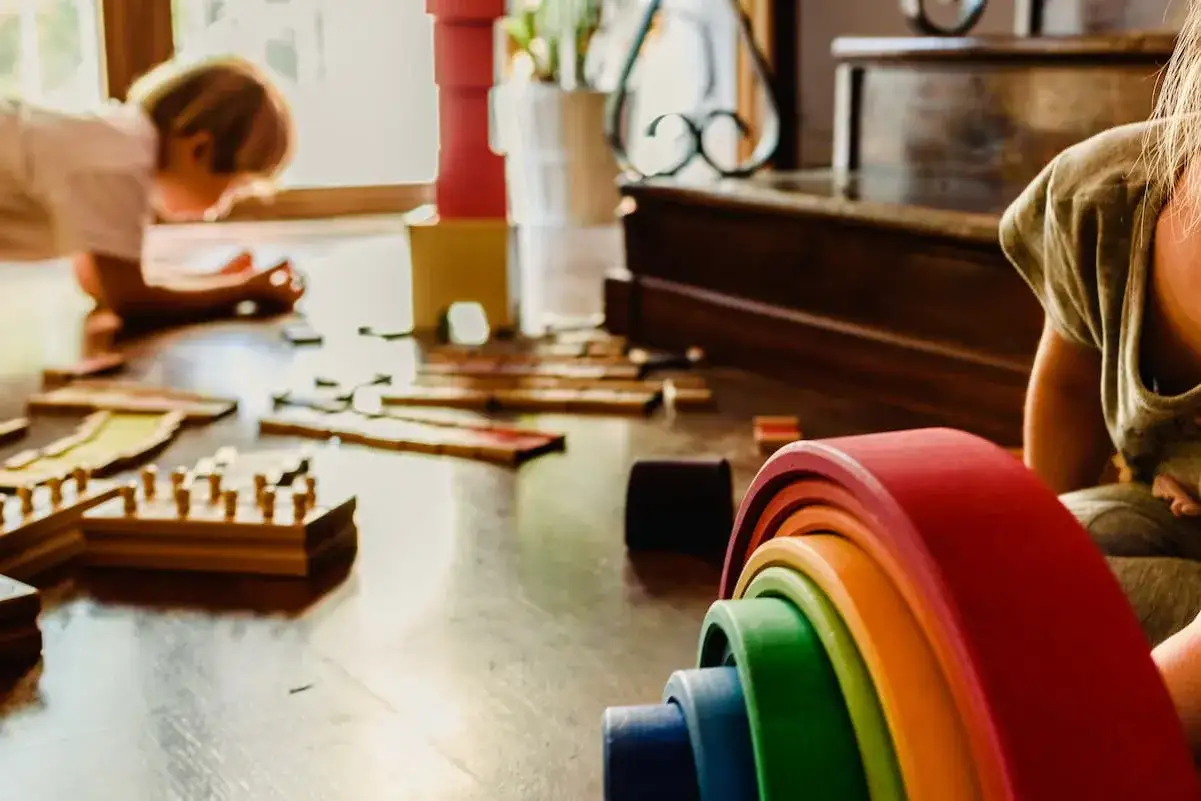 Bambini giocano con materiali Montessori, un arcobaleno di legno e blocchi. Un riassunto breve dell'apprendimento attivo.