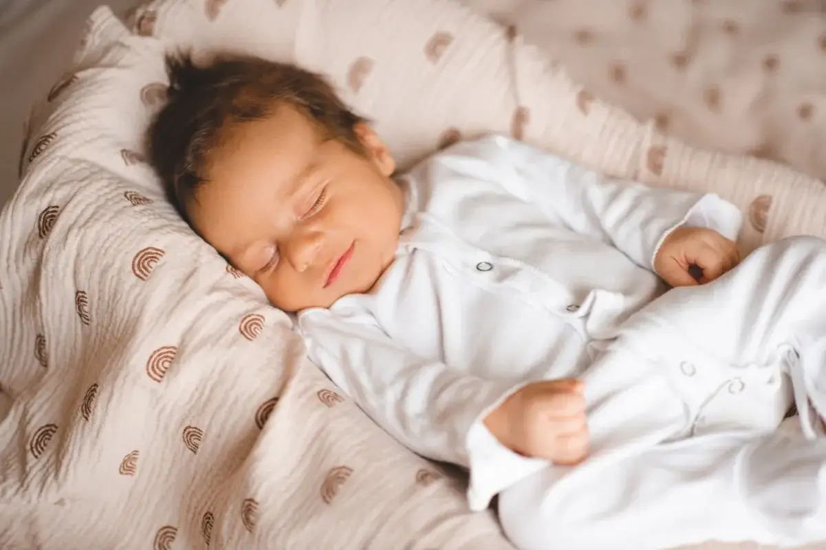 Un neonato dorme sereno, avvolto in una copertina con arcobaleni. Chiss&agrave; quali mondi incantati esplorano i neonati sognano.