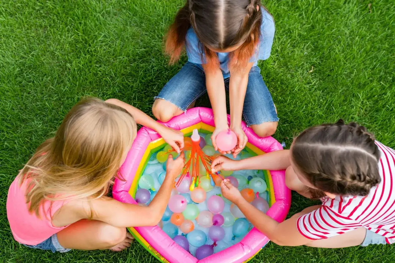 Bambine si divertono con palloncini d'acqua, perfetti giochi per feste di compleanno 7-8 anni.