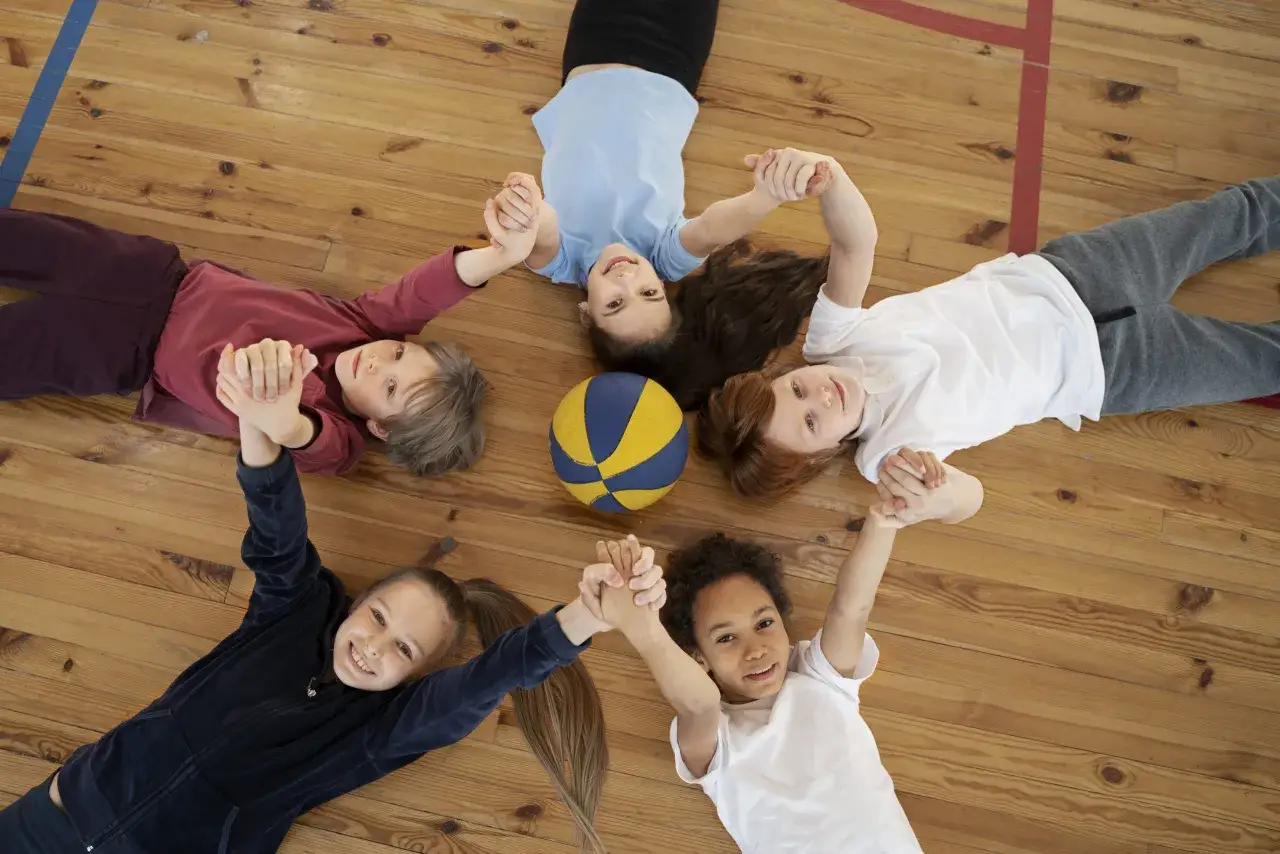 Bambini felici che si tengono per mano attorno a un pallone, un momento di gioia nello sport per bambini.