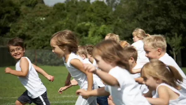 Bambini in corsa su un prato verde, felici di fare sport.