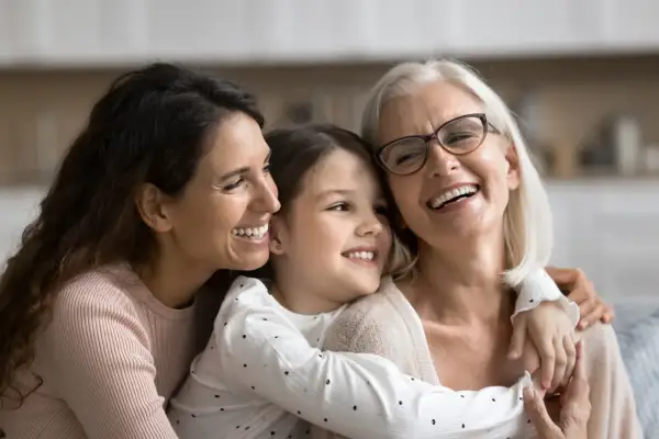 Tre generazioni di donne sorridono felici, un abbraccio che ricorda le più belle canzoni per la festa della mamma.