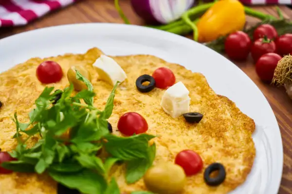 Frittata per bambini, colorata con pomodorini, olive, cubetti di formaggio e rucola. Un piatto gustoso e invitante.