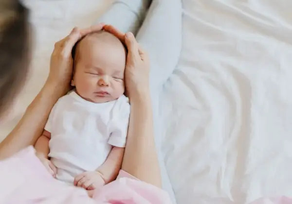 Mani che accarezzano la testa di un neonato addormentato. Il dolce rumore phon bambini lo culla nel sonno.