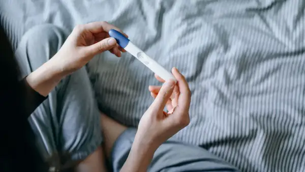 Mani che tengono un test di gravidanza, sperando in trucchi per rimanere incinta del secondo figlio.