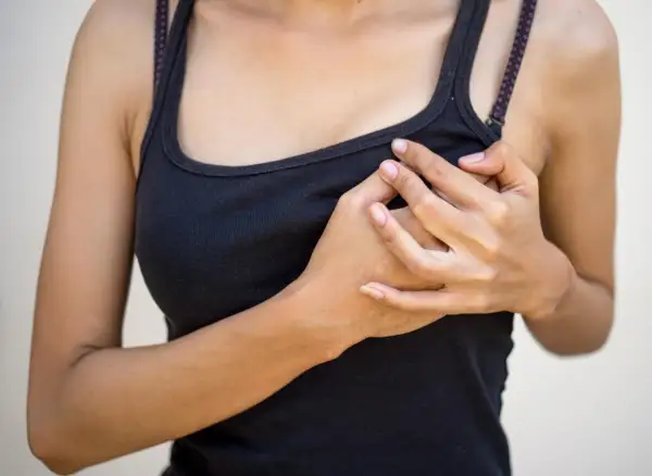 Mani che stringono il seno gonfio senza ciclo, un disagio che preoccupa.