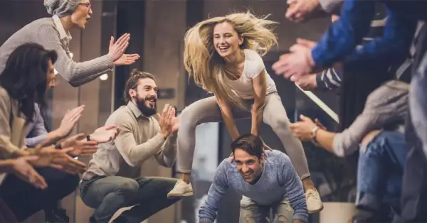 Un gruppo di amici si diverte con giochi da fare in gruppo seduti senza niente, tra risate e applausi.